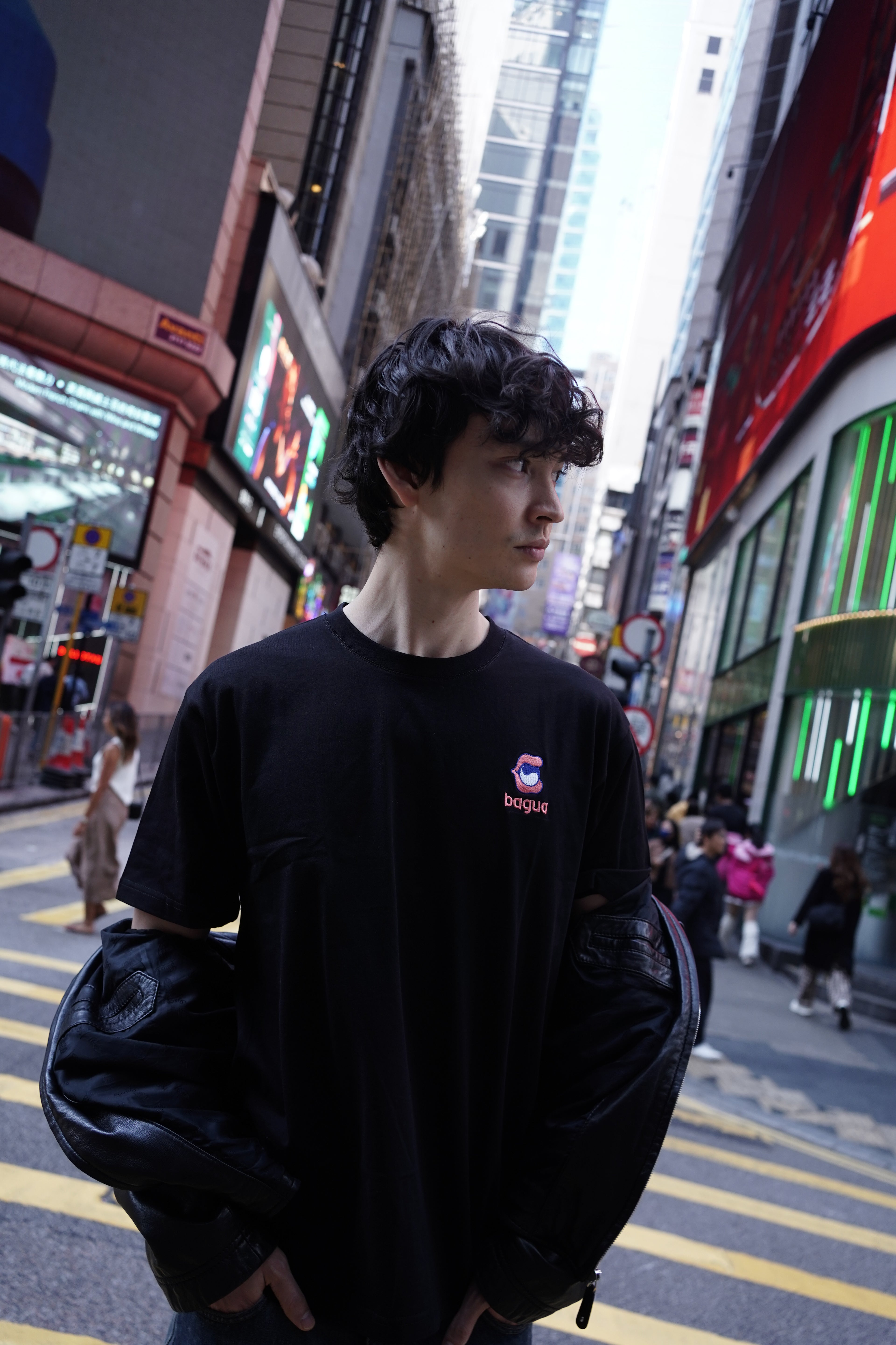 Person wearing a black tshirt with a Bagua logo in an urban setting